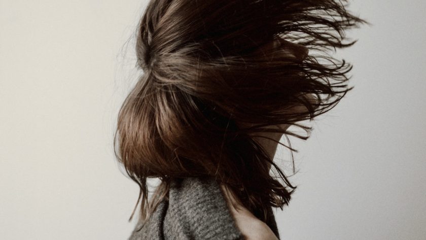 woman in gray sweater standing near white wall